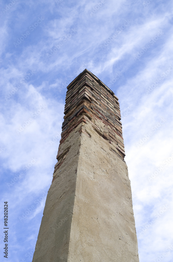 Old high brick chimney with damaged plaster
