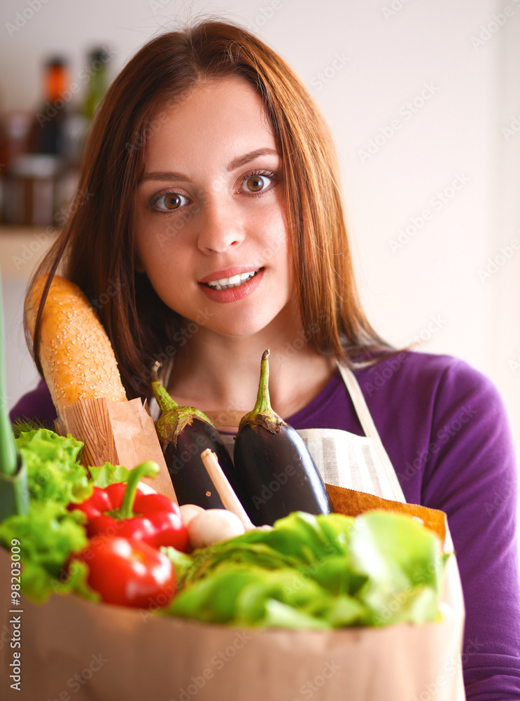 Young woman holding grocery shopping bag with vegetables Standing in the kitchen Young woman holding grocery shopping bag with vegetables Standing in the kitchen