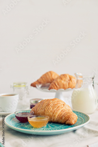 Romantic breakfast with croissant, coffee, milk, honey and jam on the table