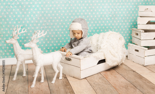 Fototapeta Naklejka Na Ścianę i Meble -  Cute child sitting in white box wearing aviator hat
