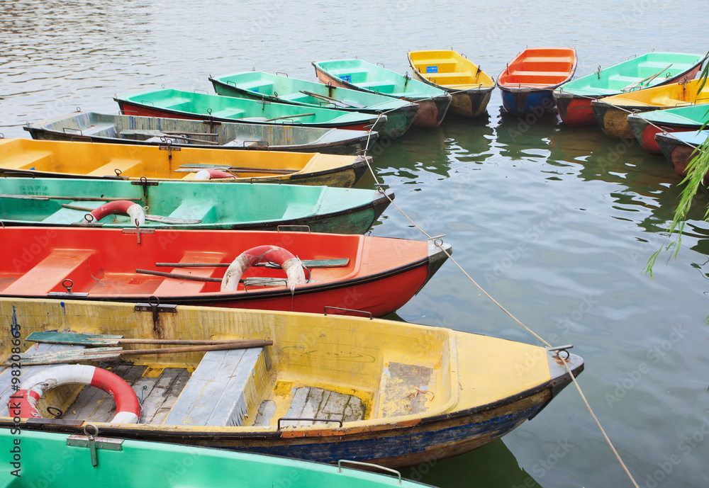 Obraz premium Aged polyester multi colored row boats moored in a lake.