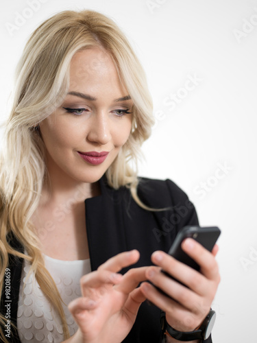 Happy businesswoman using smartphone over gray background.
