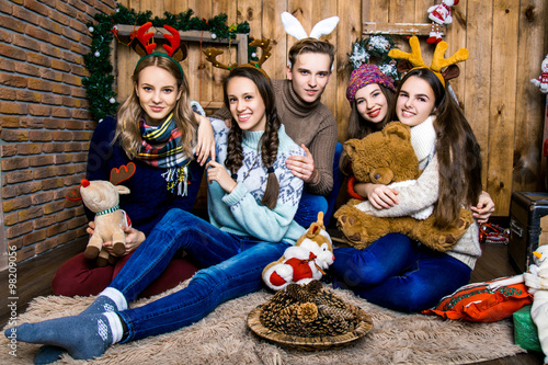 Company of boy and four girls with gifts in the room with woode