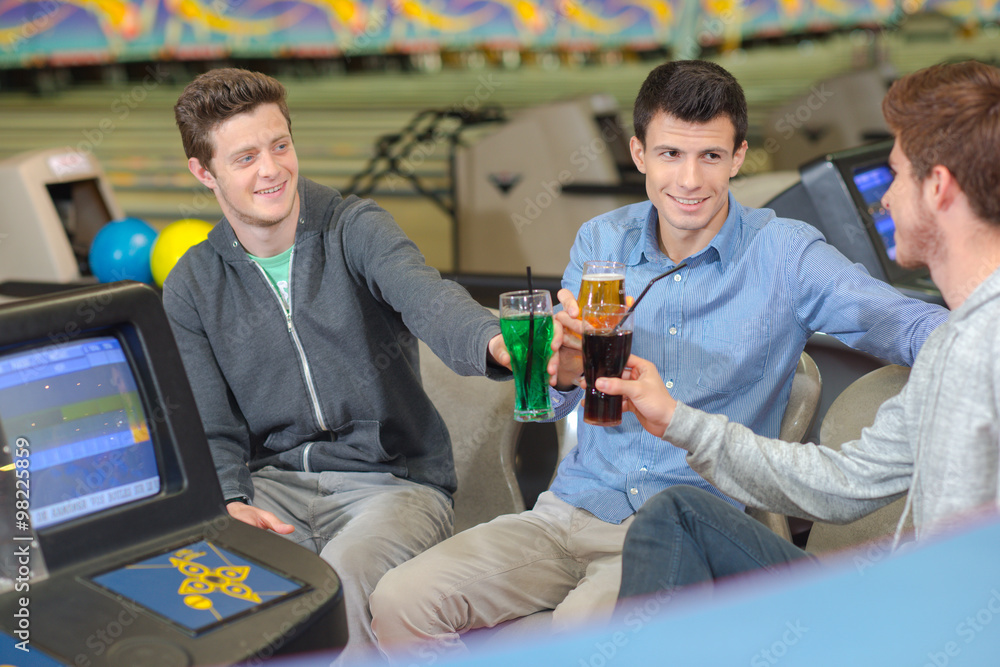 men with drinks in the bowling center