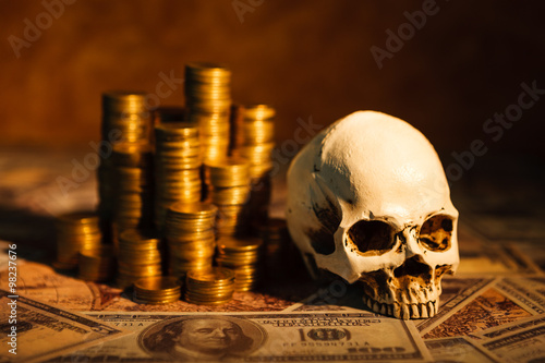 Foto Capitalism concept : Skull on bank note, coin stack and vintage