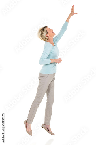 senior woman jumping up and reaching out photo