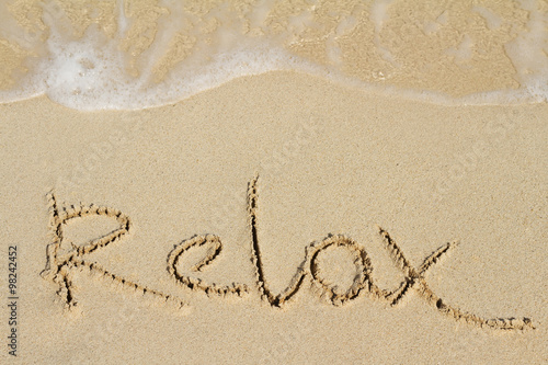 Word Relax is handwritten on sand of tropical beach © Oleandra9