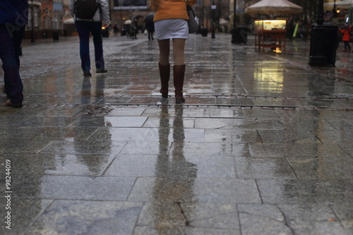 Walking along wet pavement street. Rain in the city.