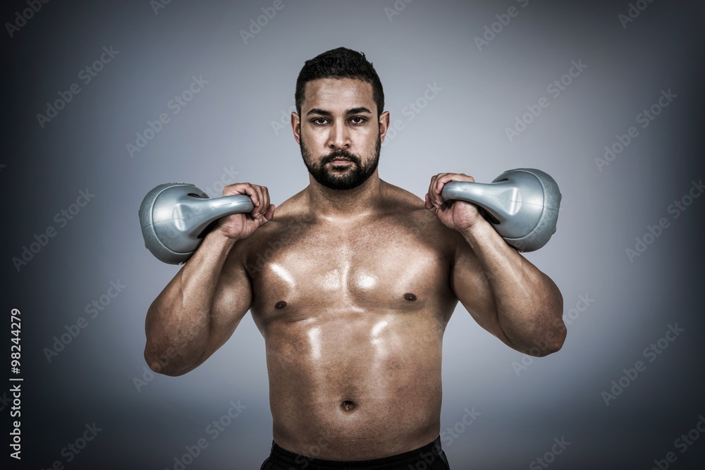 Composite image of muscular man lifting heavy kettlebell 