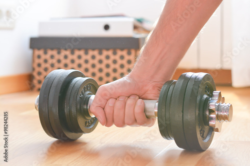 Young man doing exercises with dumbbells at home