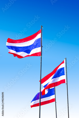 waving Thai flag of Thailand with blue sky background.