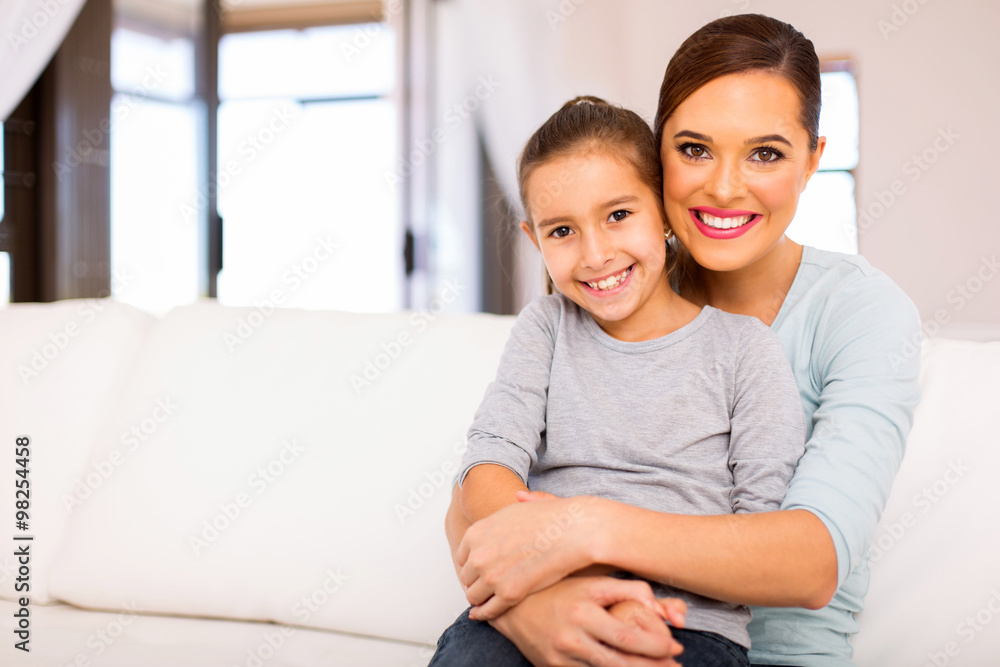 young woman sitting on couch with her daughter young woman sitting on couch with her daughter