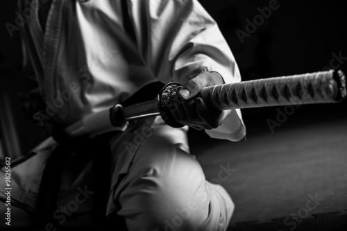Close up of young martial arts fighter with katana siting in seiza position, black and white.