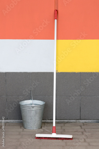 Mop and bucket against the wall on the pavement