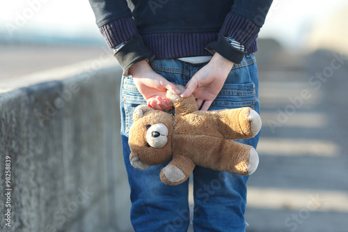 little homeless boy holding a teddy bear