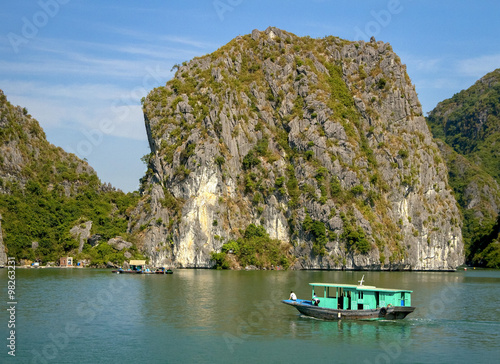 Green fishing boat in front of limestone rock in Vietnam's Ha Long Bay © dmussman