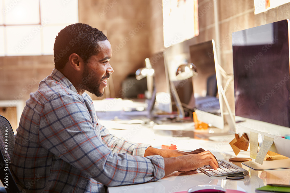 Male Designer Working At Desk In Modern Office Male Designer Working At Desk In Modern Office