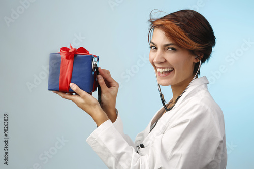 dottore sorridente gioca con lo stetoscopio con un regalo di natale photo