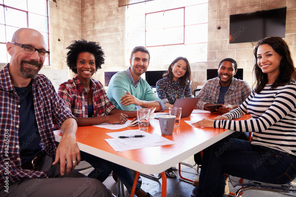Group Of Designers Having Meeting Around Table In Office Group Of Designers Having Meeting Around Table In Office