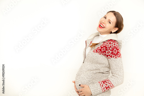 Happy, young pregnant woman in a winter clothing on a white background