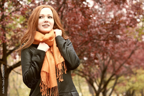 redhead girl in city park on red tree background  fall season