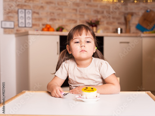 unhappy little girl with spoon and cake