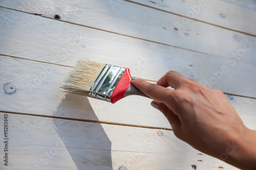 Painting on the wooden furniture with brush in hand