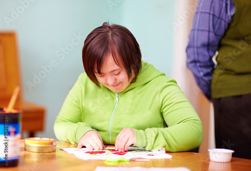 young adult woman with disability engaged in craftsmanship in rehabilitation center