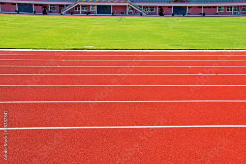 Red treadmill, track running at the stadium with green grass