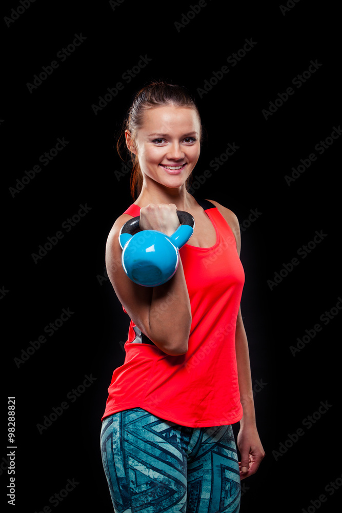 Fitness young woman in red shirt standing with kettlebells on black background Fitness young woman in red shirt standing with kettlebells on black background