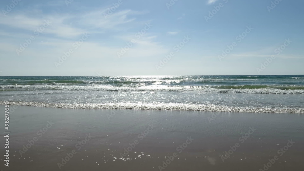 landscape beach from seaside with golden sand, blue green ocean water waves with sun reflecting and horizon blue sky in Cadiz Spain landscape beach from seaside with golden sand, blue green ocean water waves with sun reflecting and horizon blue sky in Cadiz Spain