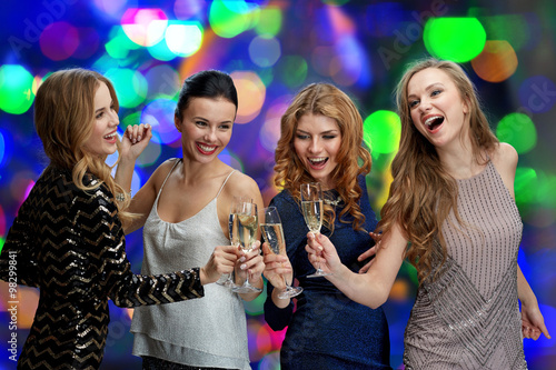 happy women clinking champagne glasses over lights