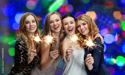 happy young women with sparklers over lights