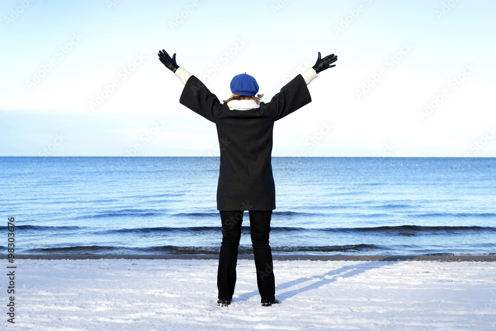 pregnant lady spreading her arms above winter sea