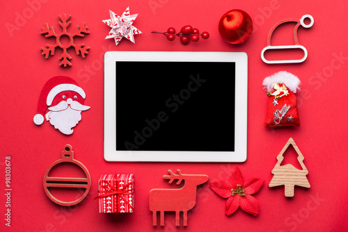 Merry Christmas and Happy New Year red background with decoration and tablet.