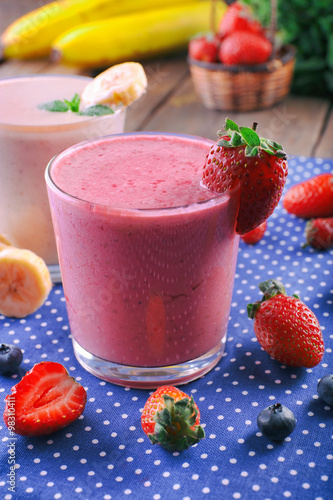 Glasses of fresh cold smoothie with fruit and berries  on blue tablecloth background