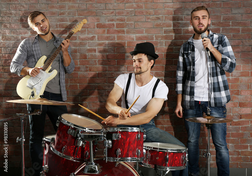 Musicians playing the drums on brick wall background photo