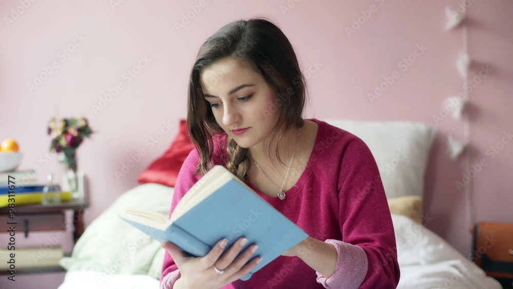 Teenage girl sitting on her bed and reading absorbing book
Teenage girl sitting on her bed and reading absorbing book