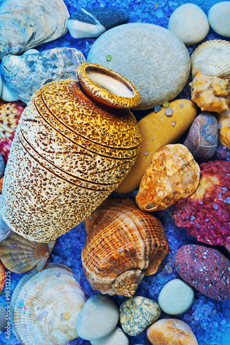 Seashells, pebbles and a vase on a background of sea salt