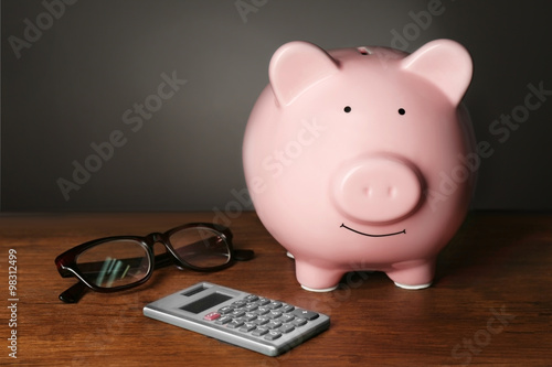 Piggy bank and calculator on table , gray background