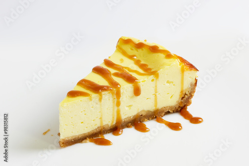 Slice of cheesecake topped with caramel sauce isolated, close up