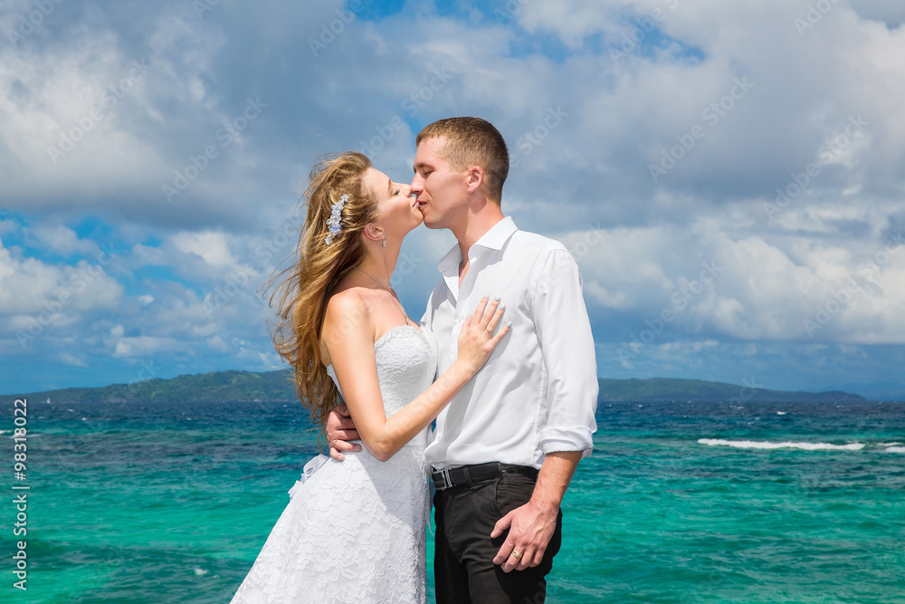 Happy bride and groom having fun on a tropical beach under the p Happy bride and groom having fun on a tropical beach under the p