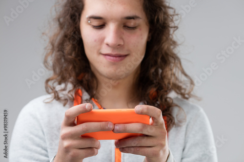 long haired young man using an orange smartphone photo