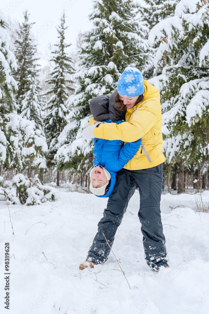 Outdoor portrait Mom plays with child in winter. She hugging her son