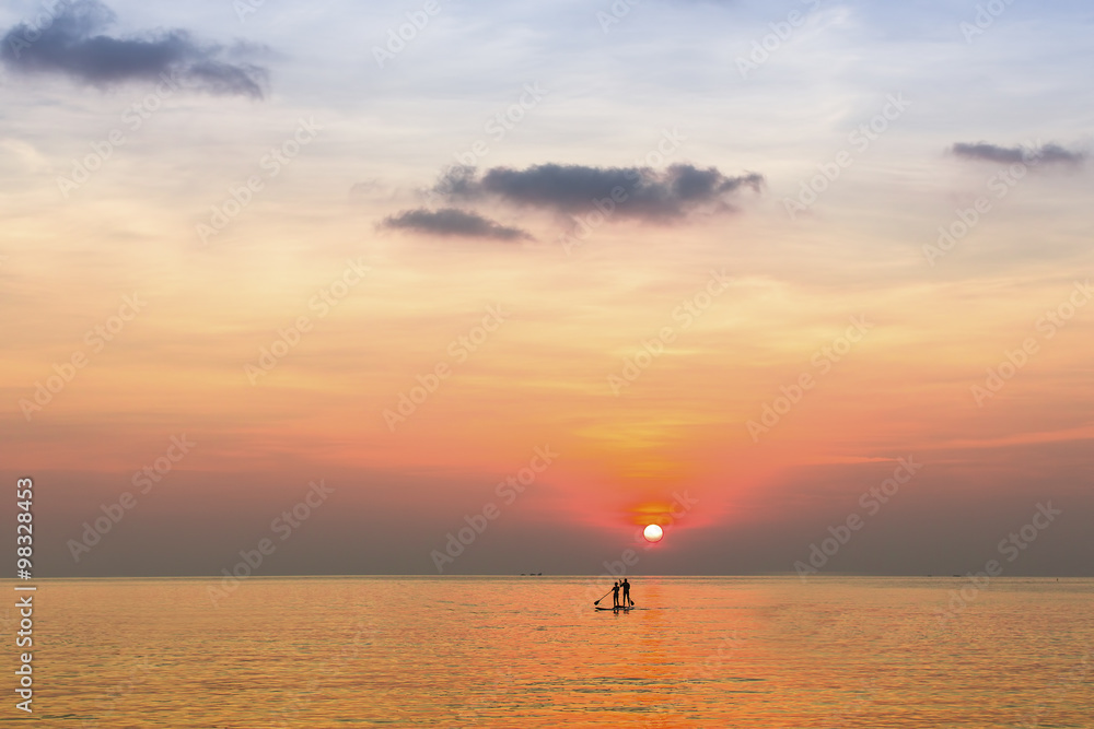 Small silhouettes of couple on the boards in the sea during beautiful sunset in the Sea.