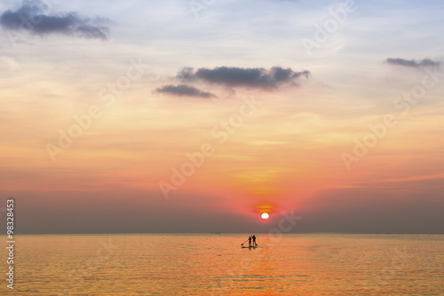 Small silhouettes of couple on the boards in the sea during beautiful sunset in the Sea.