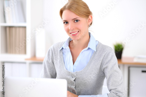 Young blonde business woman with laptop in the office. Business concept.