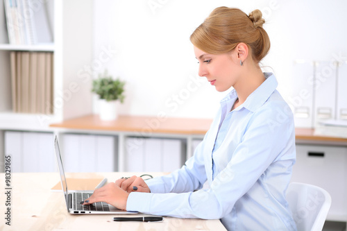 Young blonde business woman with laptop in the office. Business concept.