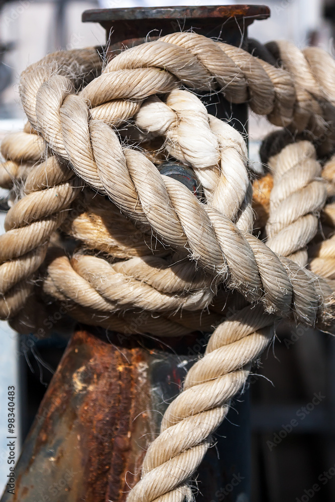 A thick rope wrapped around mooring bollard. A thick rope wrapped around mooring bollard.