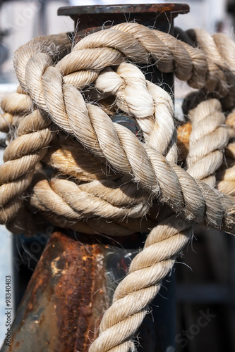 A thick rope wrapped around mooring bollard.